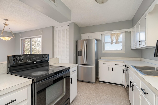 kitchen with plenty of natural light, appliances with stainless steel finishes, light countertops, and a sink