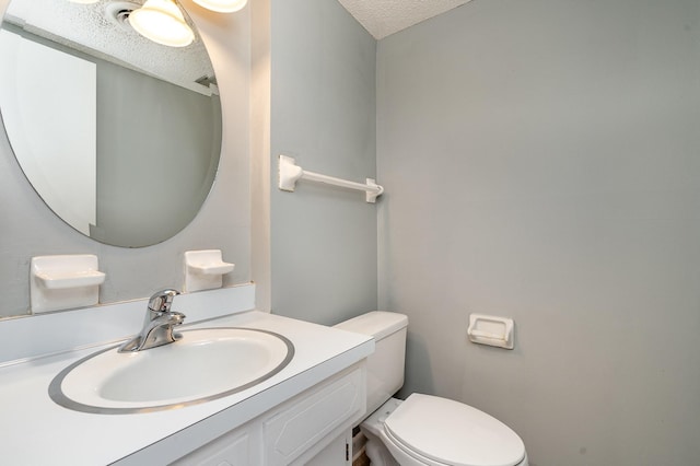 bathroom with toilet, a textured ceiling, and vanity