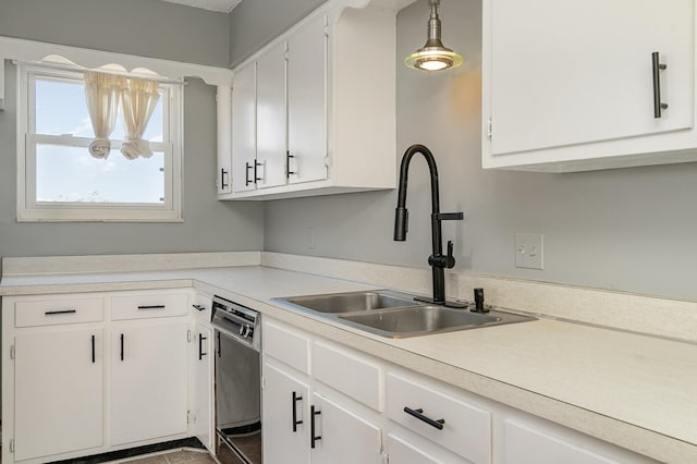 kitchen with light countertops, hanging light fixtures, white cabinets, a sink, and dishwashing machine