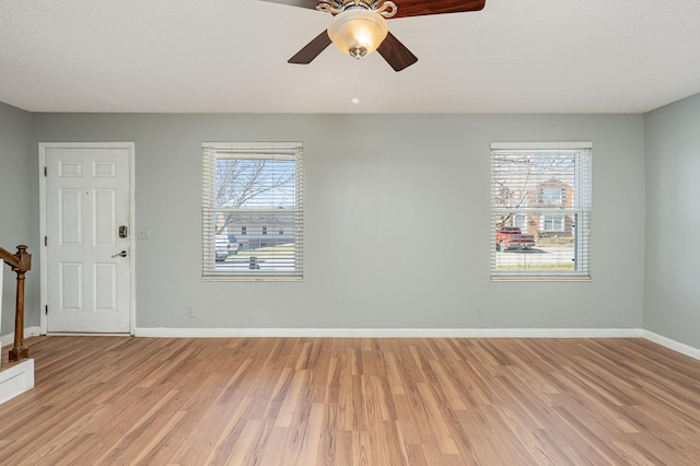 interior space featuring light wood-style floors, stairway, baseboards, and a ceiling fan