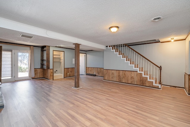 below grade area featuring a wainscoted wall, stairway, visible vents, and wood finished floors