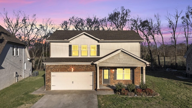 view of front of house featuring a front yard, concrete driveway, brick siding, and an attached garage