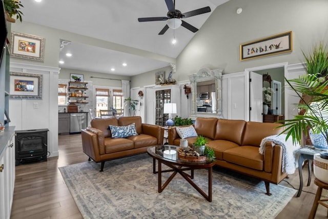 living area with recessed lighting, a ceiling fan, a wood stove, wood finished floors, and high vaulted ceiling