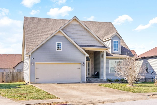 traditional-style home with a shingled roof, concrete driveway, a front yard, fence, and a garage