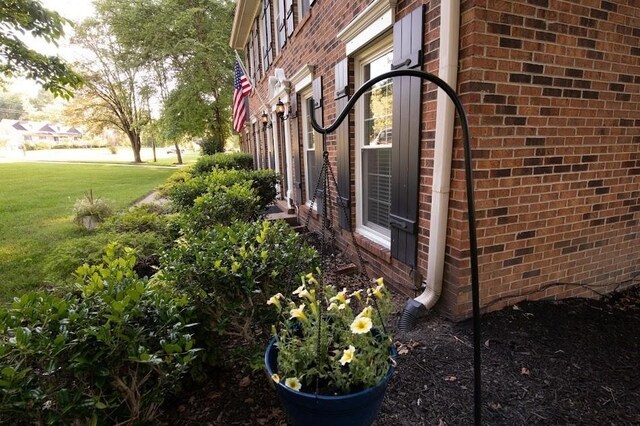 view of property exterior with brick siding and a lawn