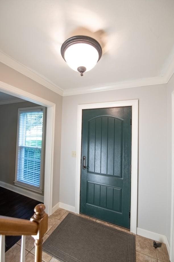 tiled foyer with crown molding and baseboards