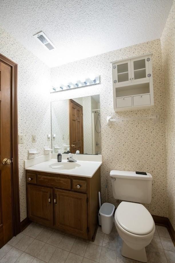 full bath featuring wallpapered walls, toilet, an enclosed shower, a textured ceiling, and vanity