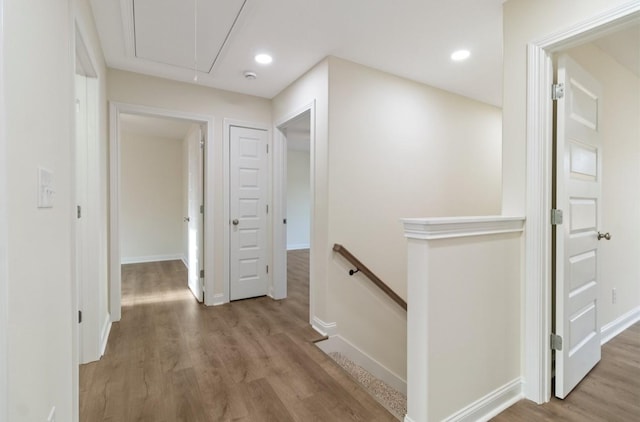 hall with recessed lighting, wood finished floors, an upstairs landing, baseboards, and attic access