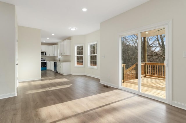 unfurnished living room with recessed lighting, visible vents, baseboards, and wood finished floors