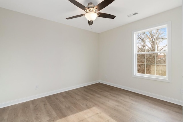 empty room with a ceiling fan, light wood-type flooring, visible vents, and baseboards