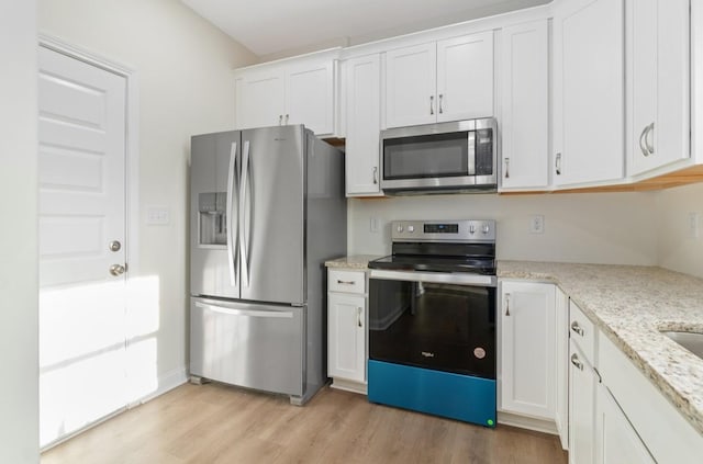 kitchen featuring appliances with stainless steel finishes, white cabinetry, light wood-style floors, and light stone countertops