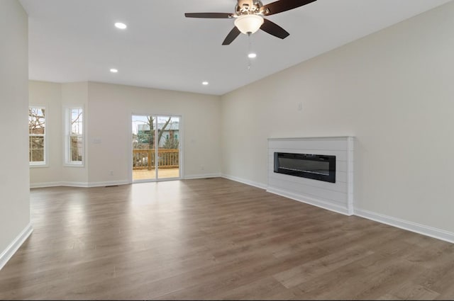 unfurnished living room featuring baseboards, wood finished floors, a glass covered fireplace, and recessed lighting