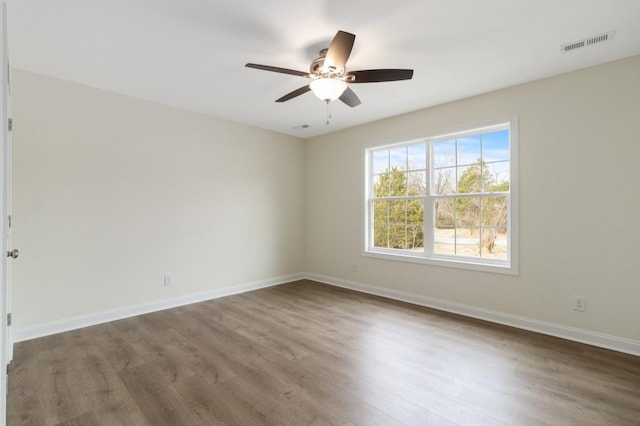 unfurnished room featuring ceiling fan, wood finished floors, visible vents, and baseboards