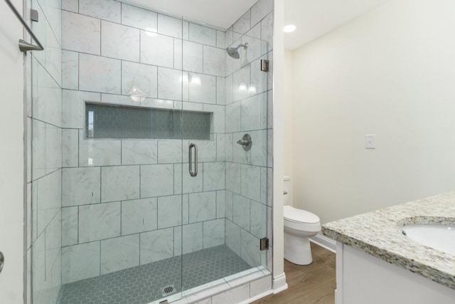 full bathroom with wood finished floors, a stall shower, vanity, and toilet