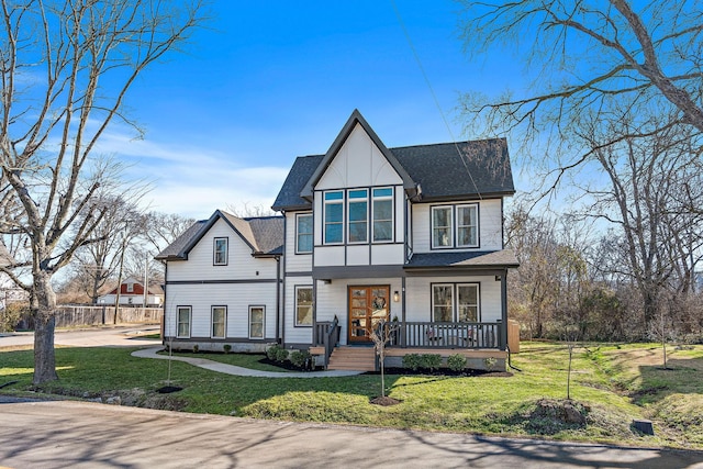 view of front facade with a porch, roof with shingles, fence, and a front lawn