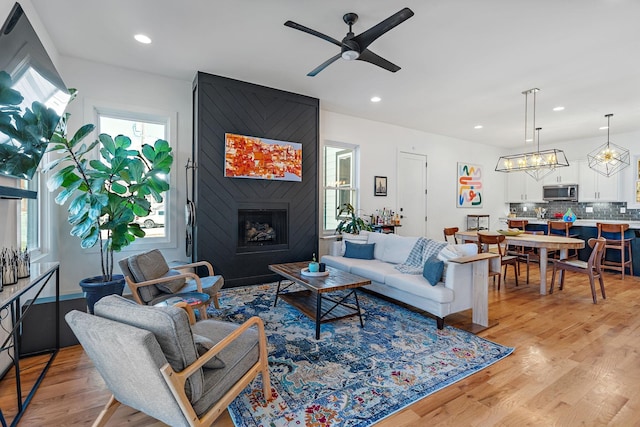 living area with a large fireplace, light wood finished floors, and recessed lighting