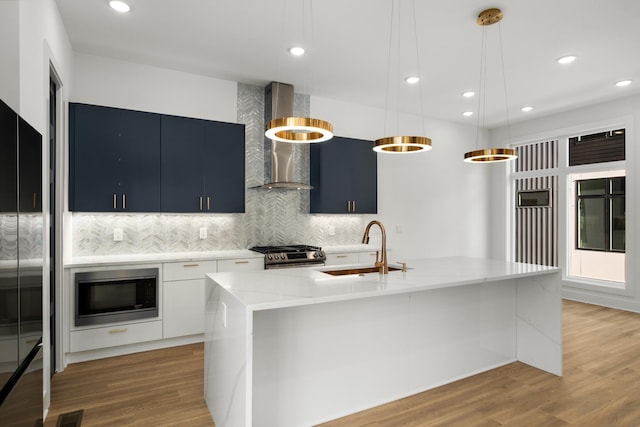 kitchen with a sink, light wood-style floors, appliances with stainless steel finishes, backsplash, and decorative light fixtures