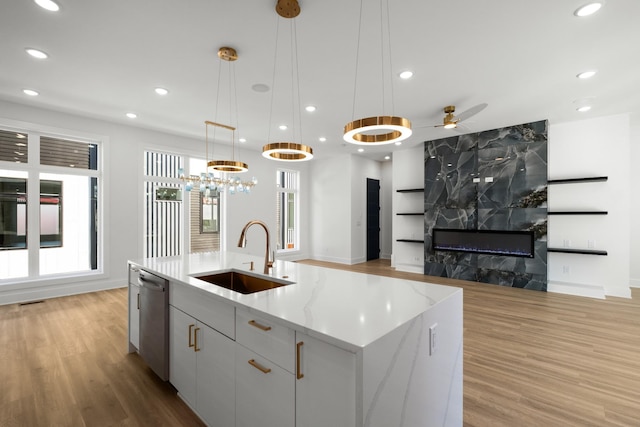 kitchen featuring light wood-type flooring, stainless steel dishwasher, open floor plan, and a sink