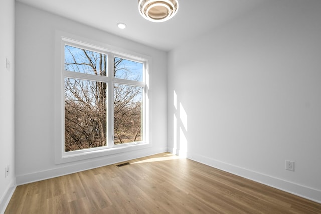 unfurnished room featuring wood finished floors, visible vents, and baseboards