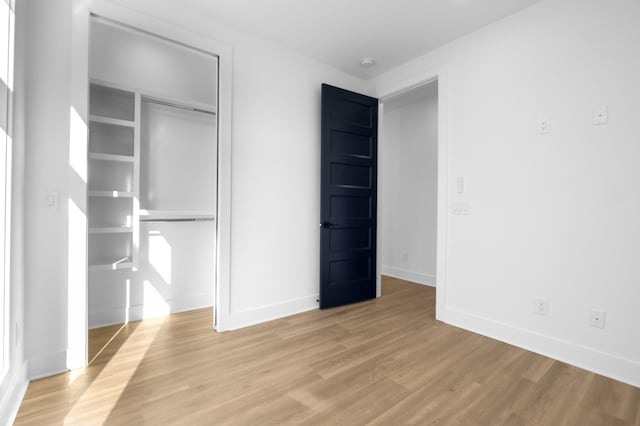 unfurnished bedroom featuring a closet, light wood-style flooring, and baseboards