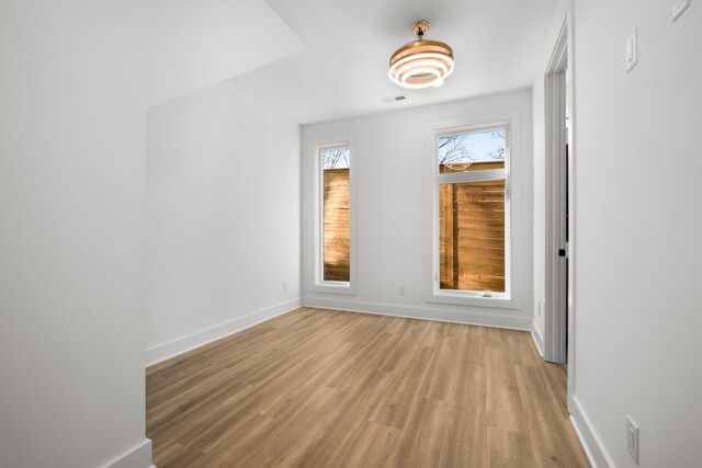 empty room featuring baseboards, visible vents, and light wood finished floors