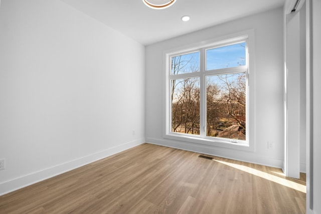 empty room with recessed lighting, wood finished floors, visible vents, and baseboards