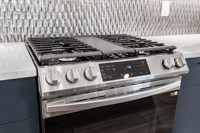 details with light stone counters, decorative backsplash, and gas range