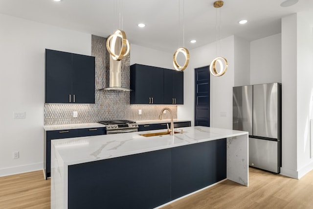 kitchen featuring dark cabinets, a sink, appliances with stainless steel finishes, light wood-type flooring, and decorative backsplash