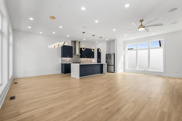 kitchen with freestanding refrigerator, open floor plan, visible vents, and wall chimney range hood