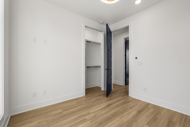 unfurnished bedroom featuring baseboards, a closet, recessed lighting, and light wood-style floors