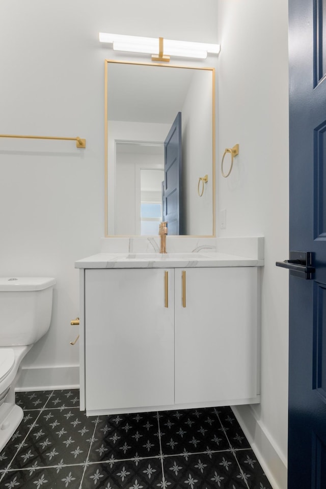 bathroom featuring vanity, toilet, and baseboards