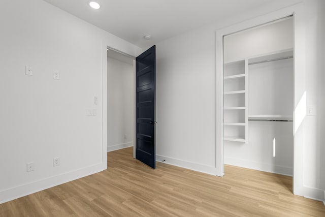 unfurnished bedroom with light wood finished floors, baseboards, a closet, and recessed lighting