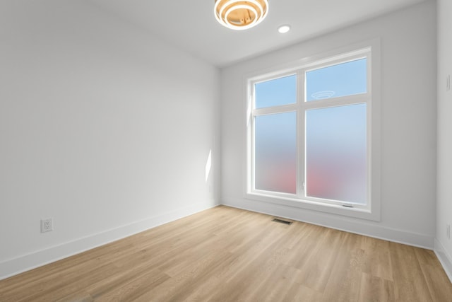 spare room with light wood-style flooring, visible vents, and baseboards