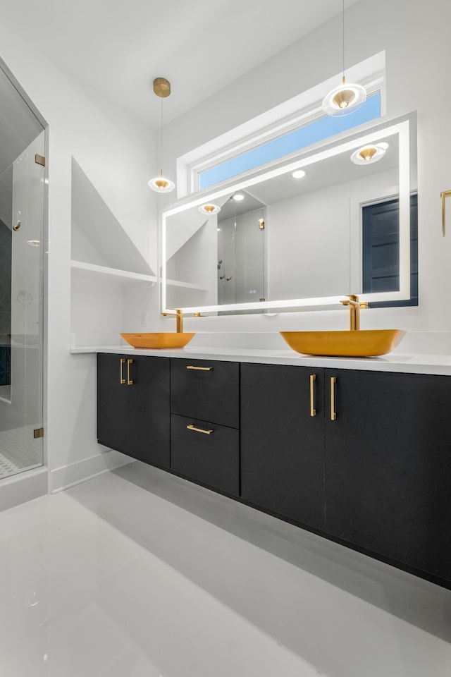 bathroom with double vanity, a stall shower, baseboards, and a sink