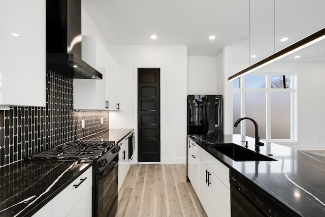 kitchen with a sink, black appliances, wall chimney exhaust hood, and modern cabinets