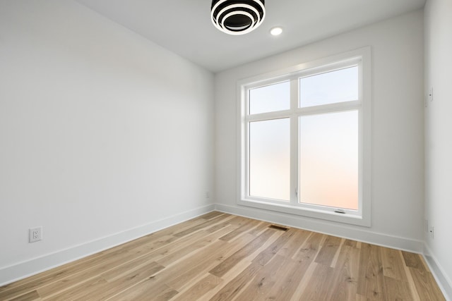 spare room with light wood-style floors, visible vents, and baseboards