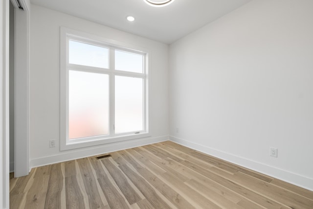 spare room with light wood-type flooring, visible vents, baseboards, and recessed lighting