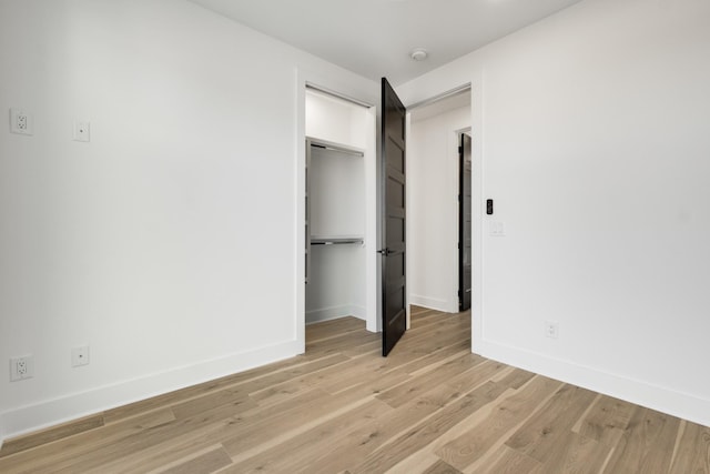 unfurnished bedroom with light wood-style floors, baseboards, and a closet