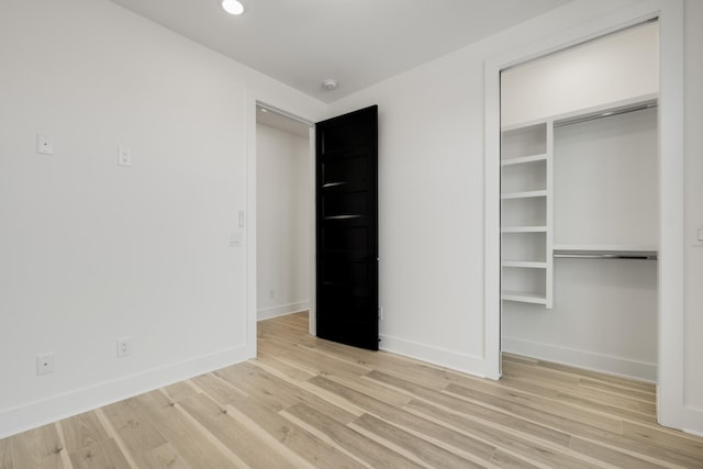 unfurnished bedroom with a closet, recessed lighting, wood finished floors, and baseboards