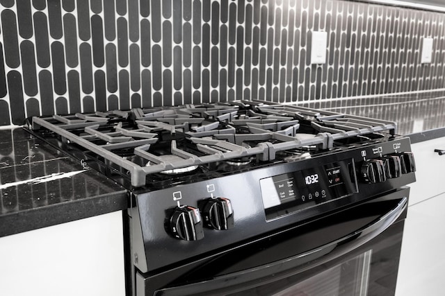 interior details featuring black gas range and decorative backsplash