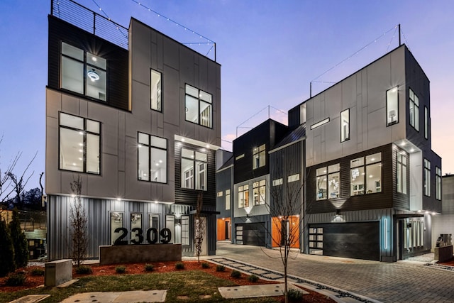 property at dusk featuring an attached garage and decorative driveway