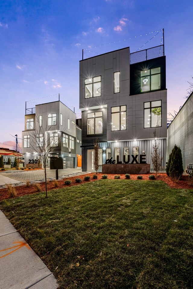 back of house at dusk featuring a yard