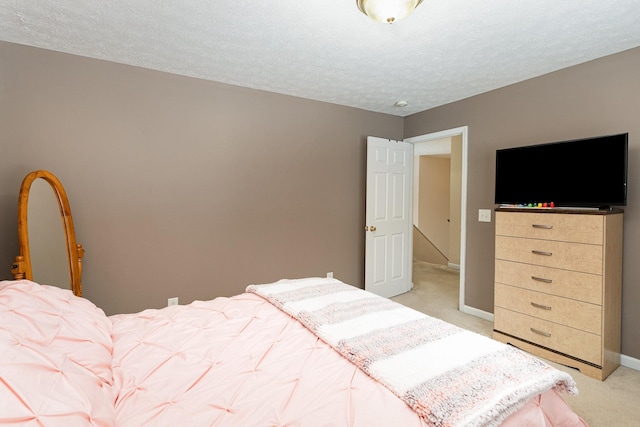 bedroom featuring light carpet, a textured ceiling, and baseboards