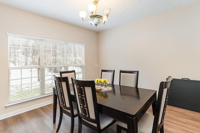 dining room featuring a healthy amount of sunlight, a notable chandelier, baseboards, and wood finished floors