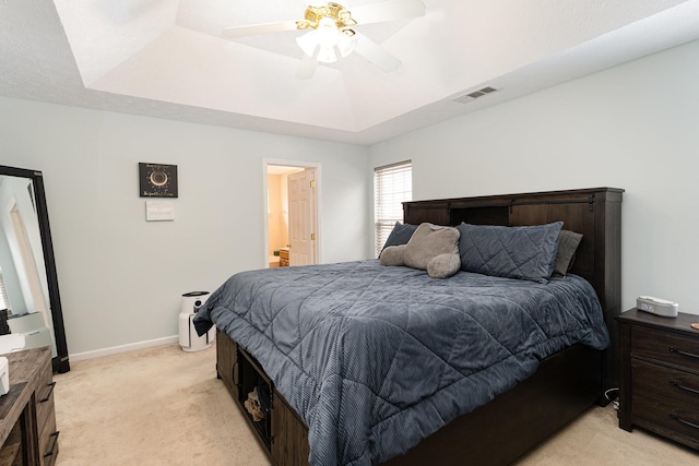 bedroom with visible vents, baseboards, a ceiling fan, light colored carpet, and a tray ceiling