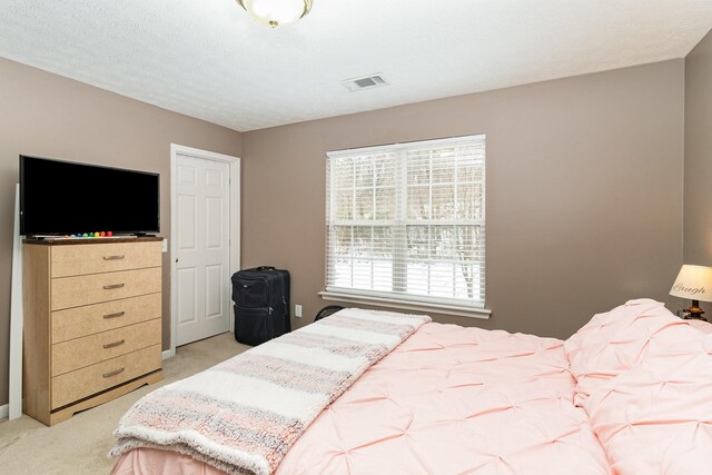 bedroom featuring light carpet, a textured ceiling, and visible vents