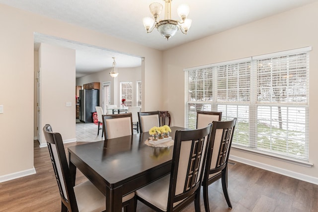 dining area with baseboards, wood finished floors, and an inviting chandelier