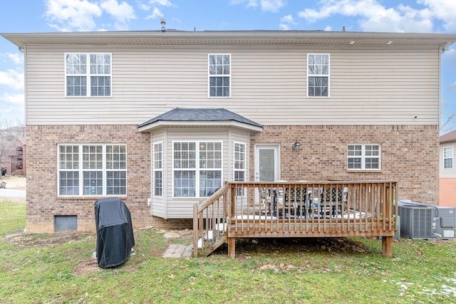 back of property with a deck, brick siding, a lawn, and cooling unit