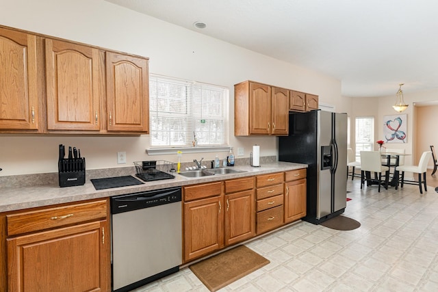 kitchen featuring brown cabinets, light floors, light countertops, appliances with stainless steel finishes, and a sink