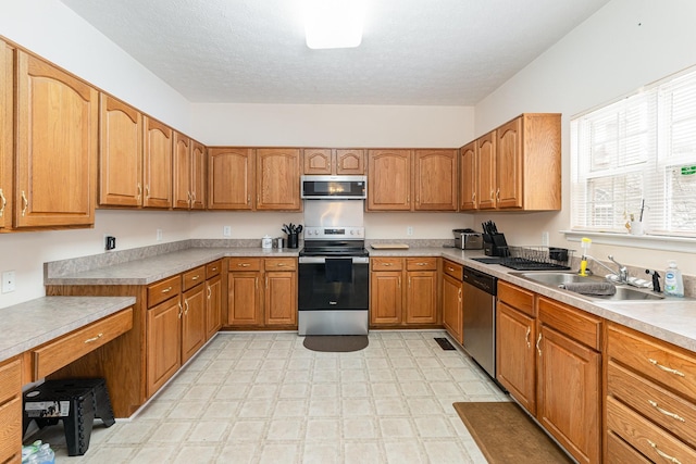 kitchen with stainless steel appliances, brown cabinets, a sink, and light floors